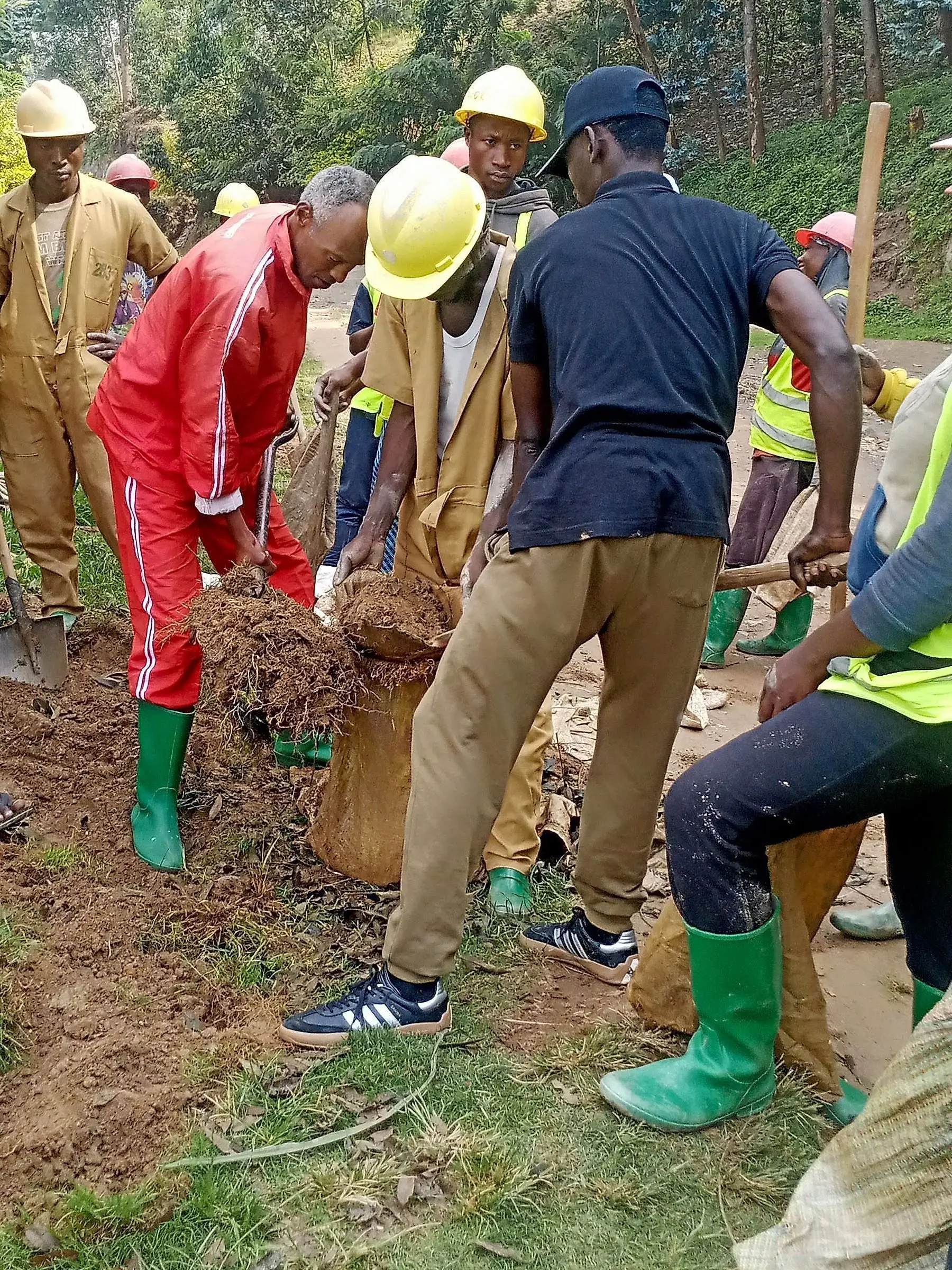 Volunteers in hard hats filling sacks while clearing a water channel