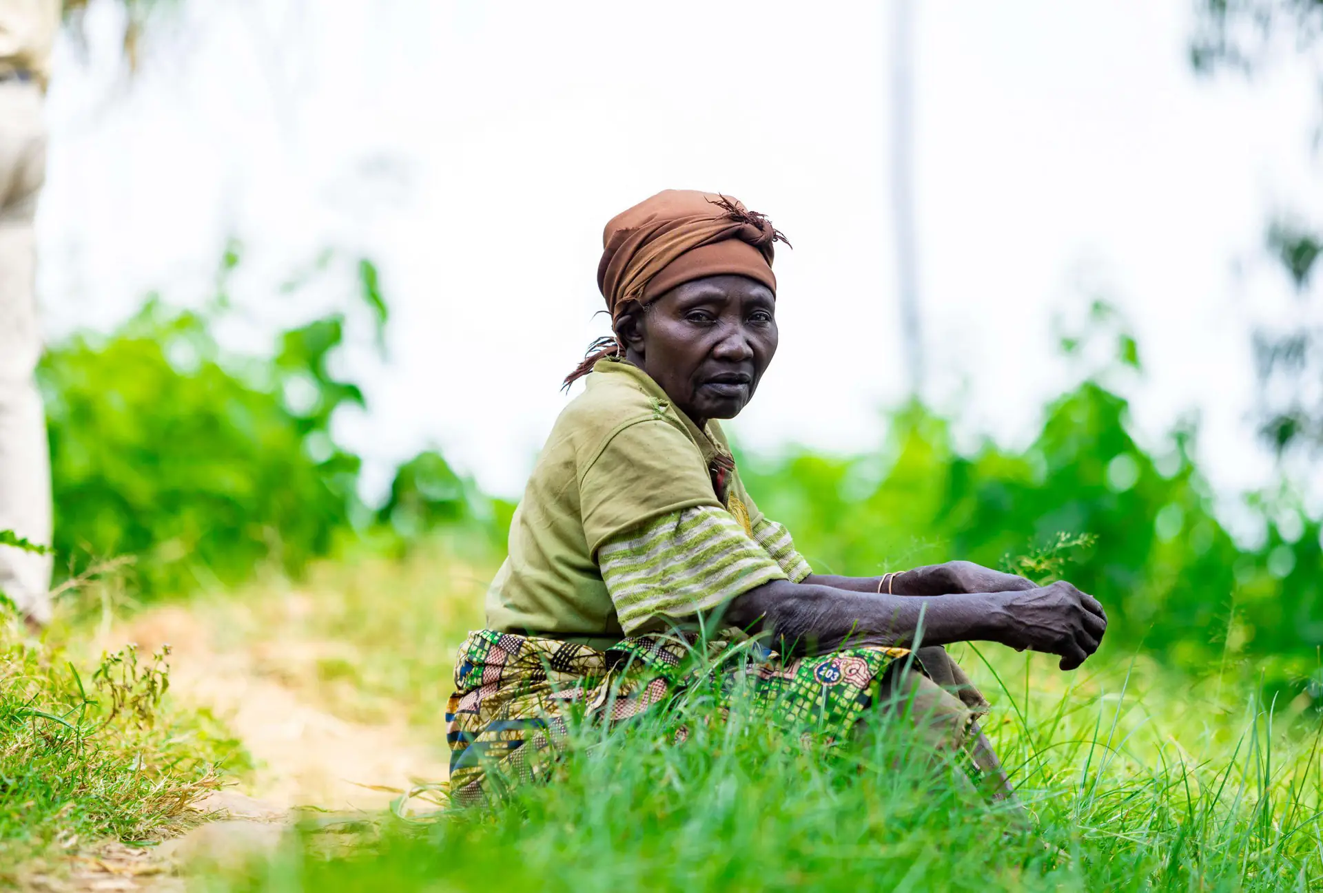 A woman resting in a green field in rural Rwanda
